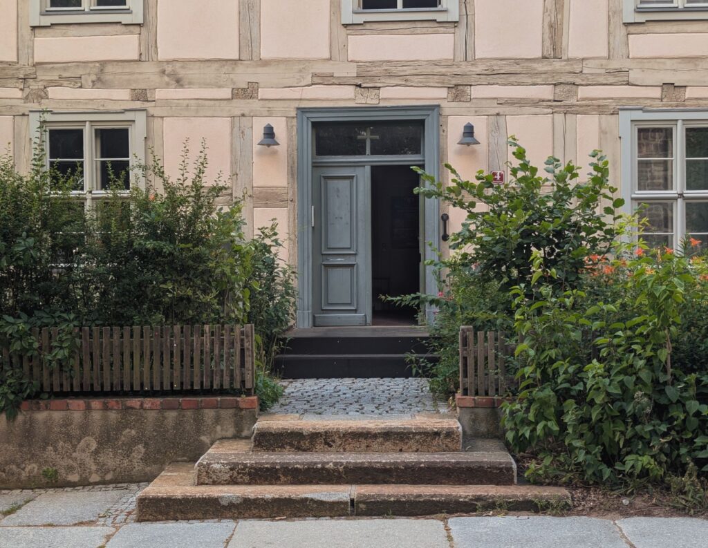 Hauseingang mit wenigen Steinstufen zwischen Grünpflanzen